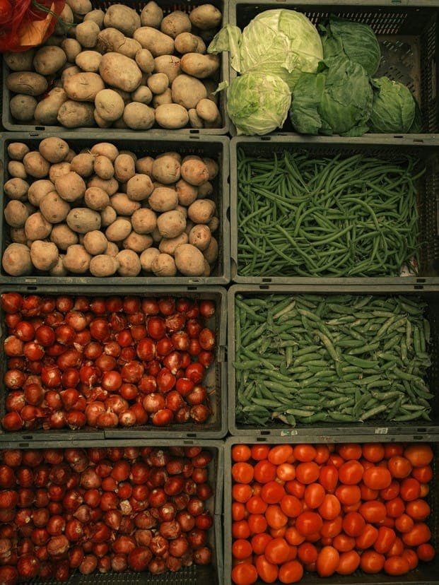 Crates of fresh produce: potatoes, beans, tomatoes and greens